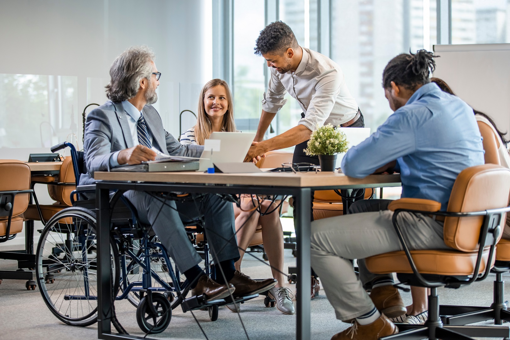 Happy businessman in wheelchair reading documents during a meeti