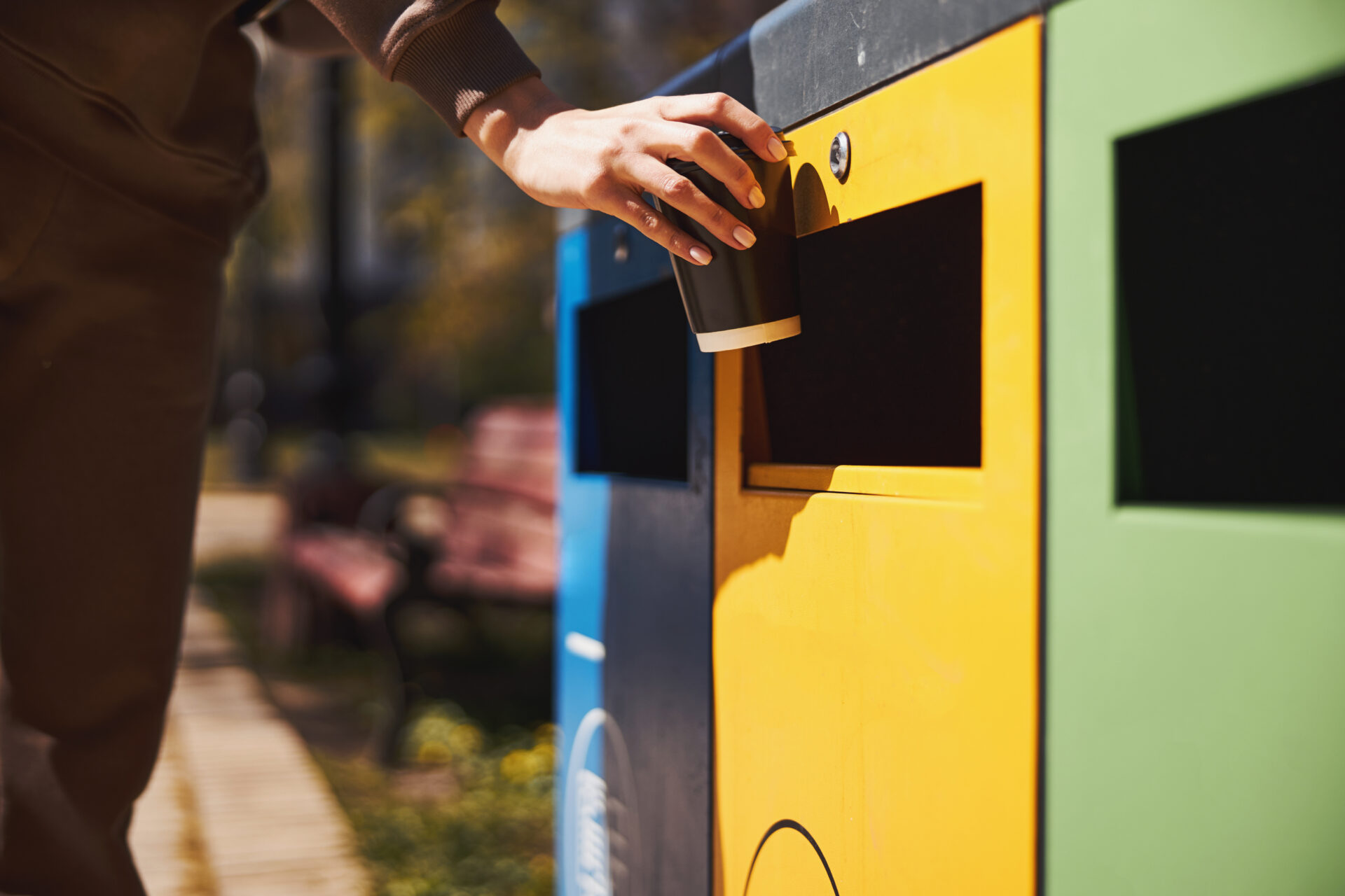 Person throwing her coffee cup into rubbish bin for plastic